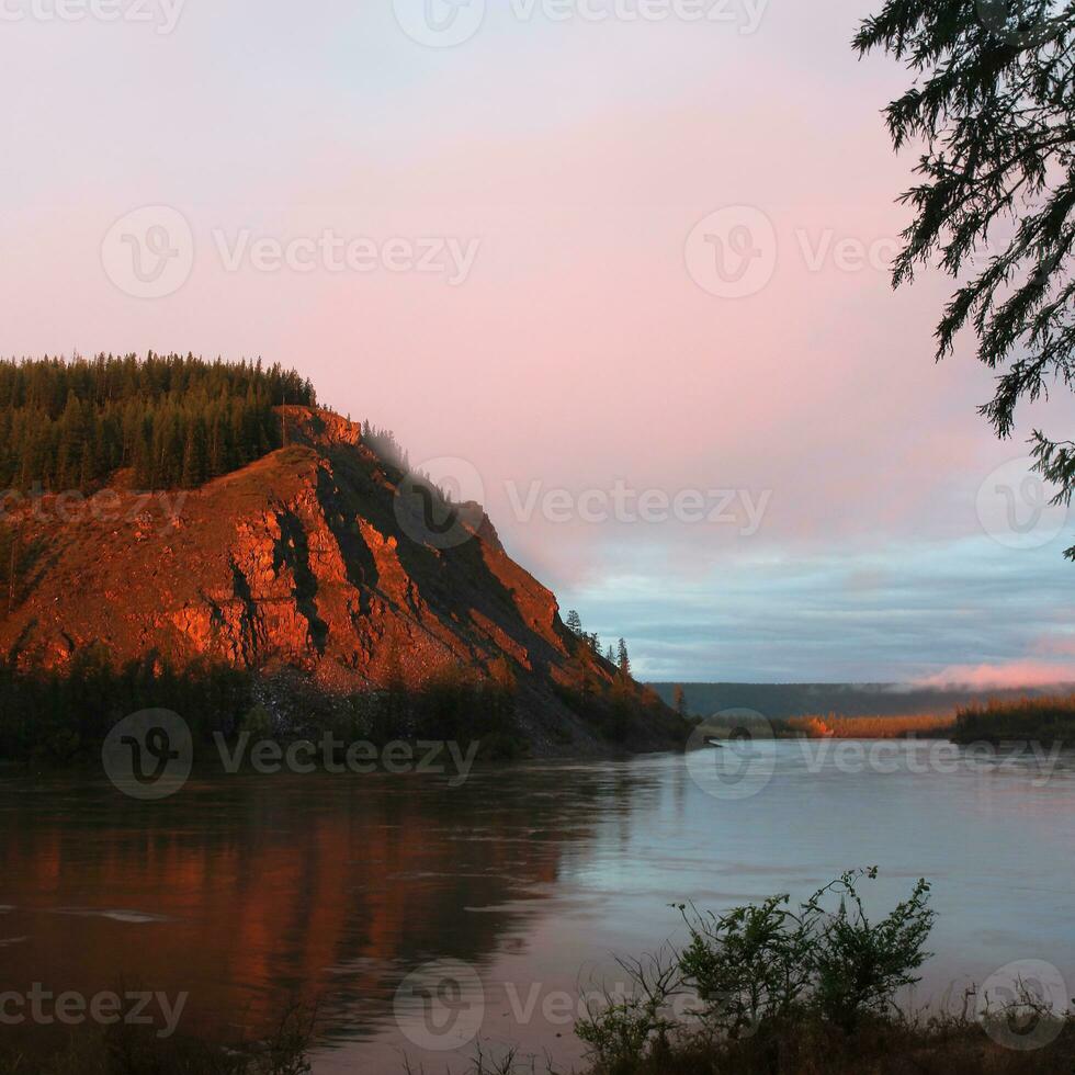 solnedgång på de nordlig flod med de berg som en bakgrund foto