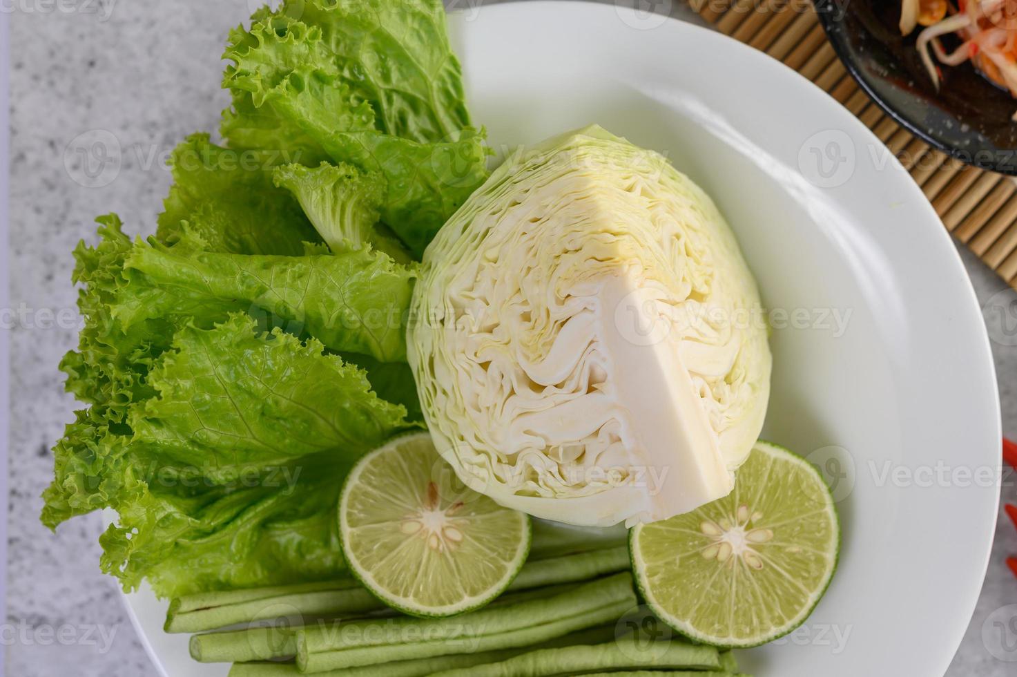 collard green, lime, gårdslånga bönor sallad på en vit tallrik foto