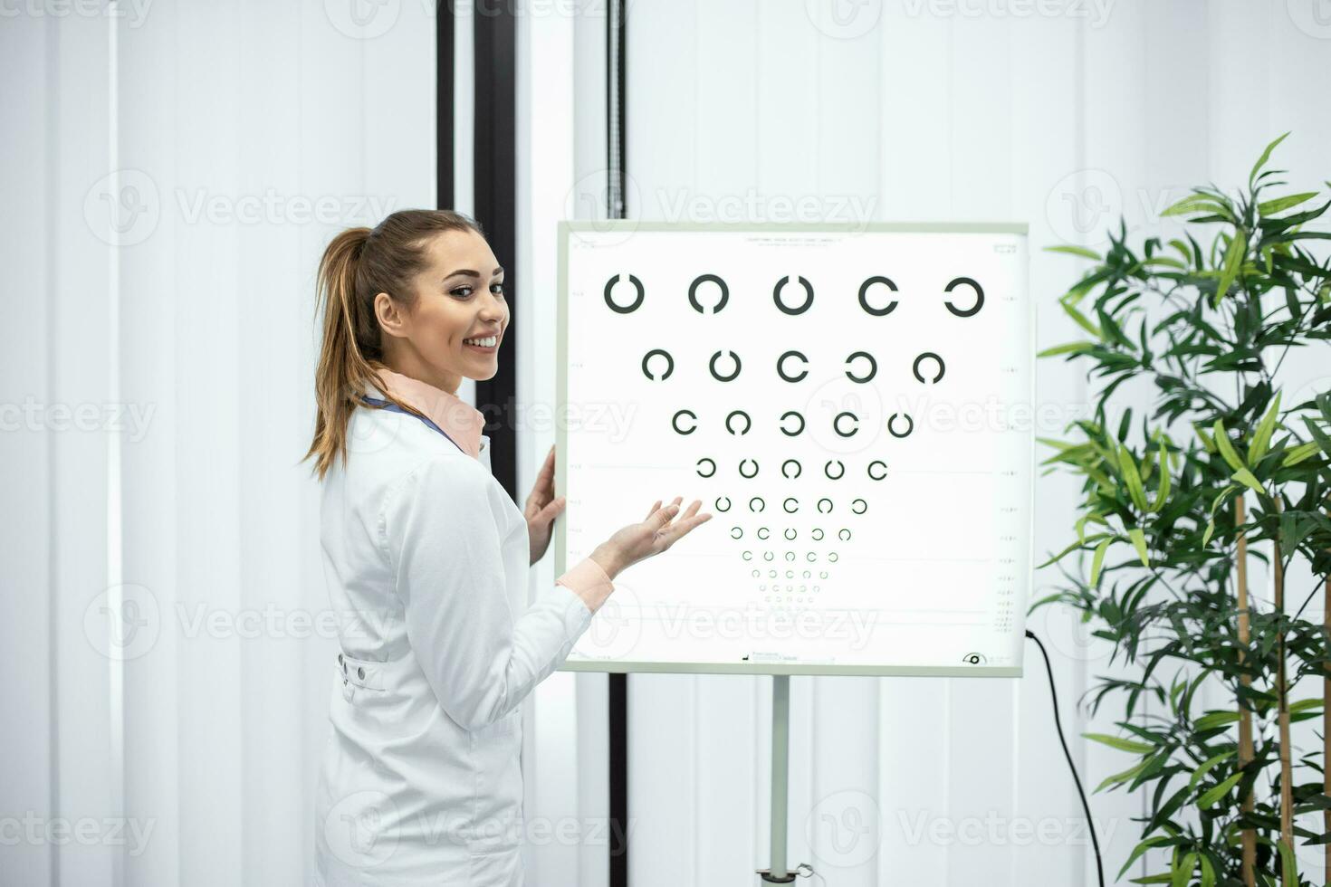 professionell kvinna optiker pekande på öga Diagram, i god tid diagnos av syn. porträtt av optiker be patient för ett öga examen testa med ett öga Diagram övervaka på hans klinik foto