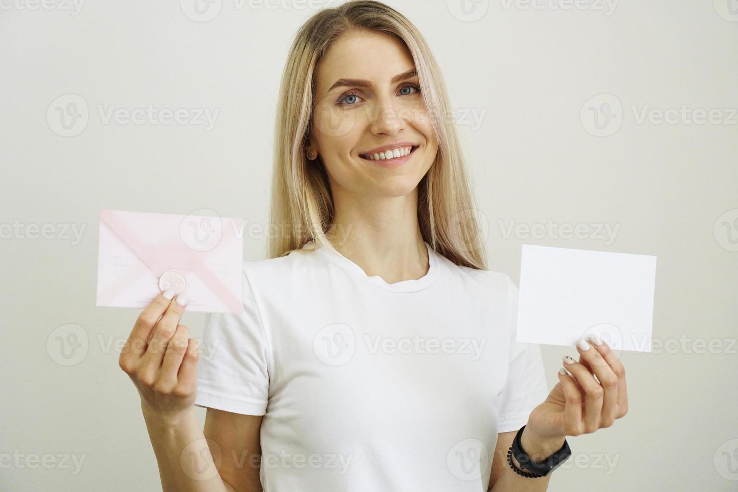 kvinna i vit t-shirt håller vitt tomt pappersark i handen foto