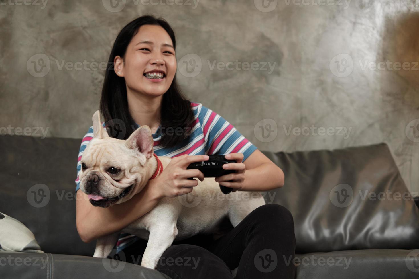 ung kvinna spelar spelkonsol med sin söta hund. foto