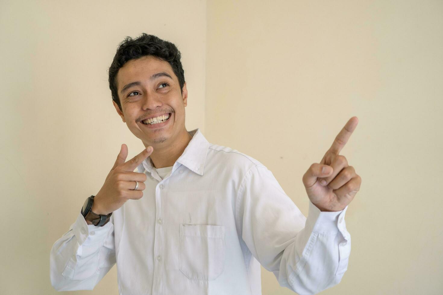 ung indonesiska lockigt man ha på sig vit kläder med Miniatyr utgör. foto