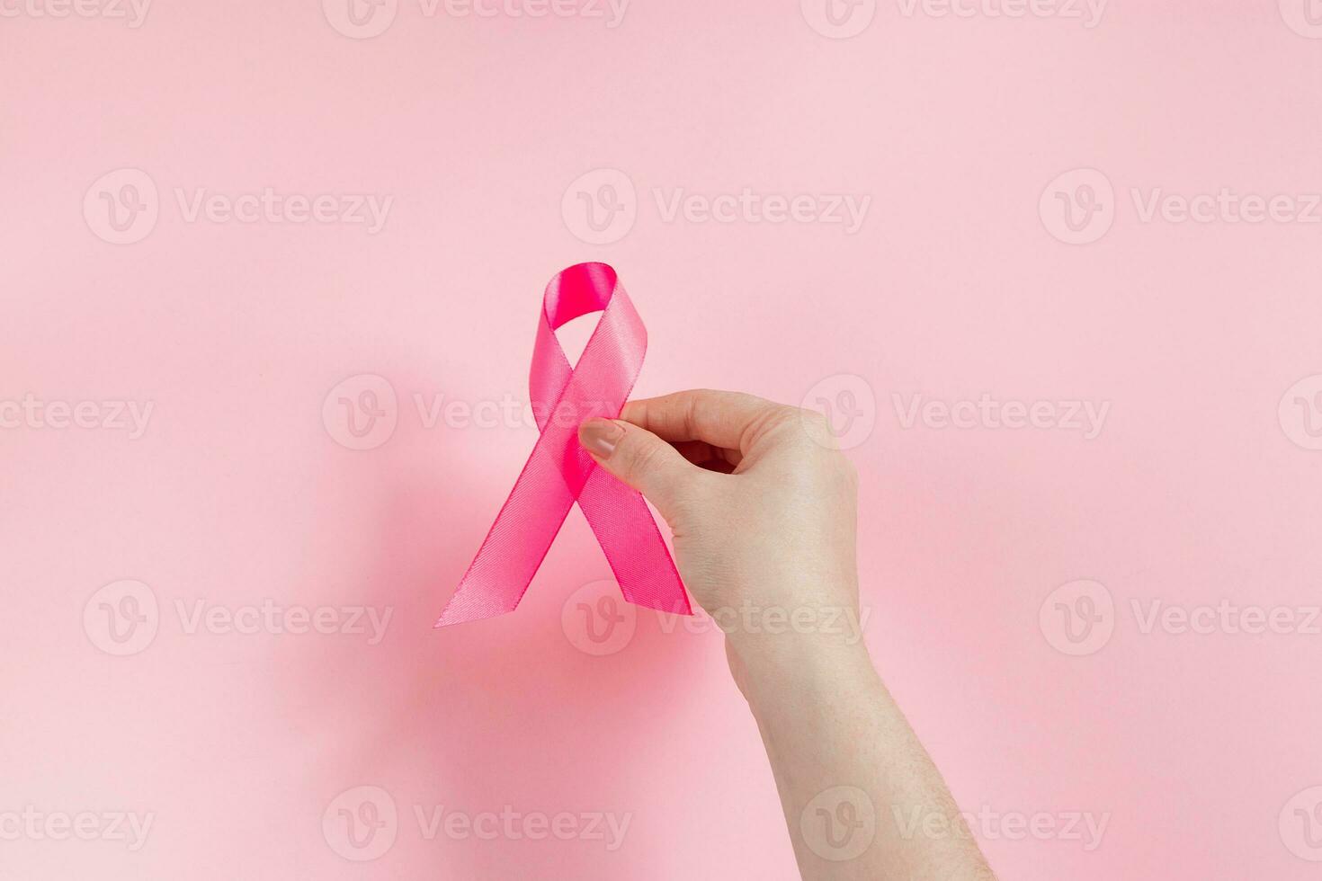 bröst cancer medvetenhet månad. kvinnas hand innehar rosa band. hälsa vård begrepp, cancer kontrollera symbol. foto