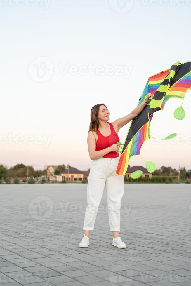 ung kvinna som flyger en drake i en offentlig park vid solnedgången foto