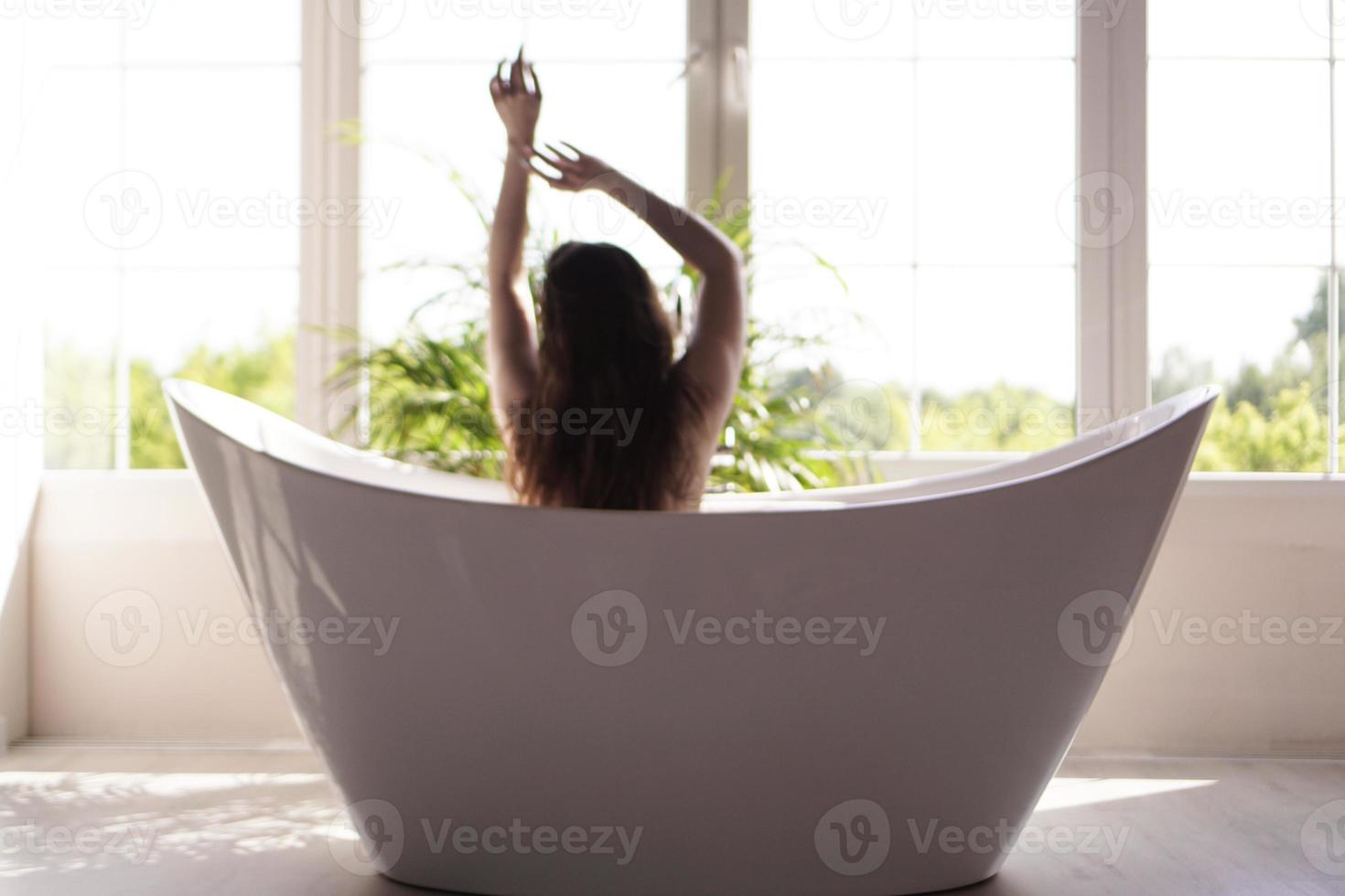 en attraktiv tjej som kopplar av i badet på ljus bakgrund. suddigt foto