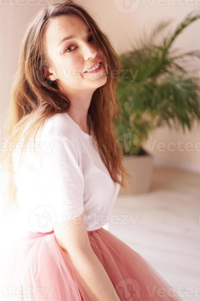 attraktiv kvinna i rosa kjol och vit t-shirt tittar på kameran foto