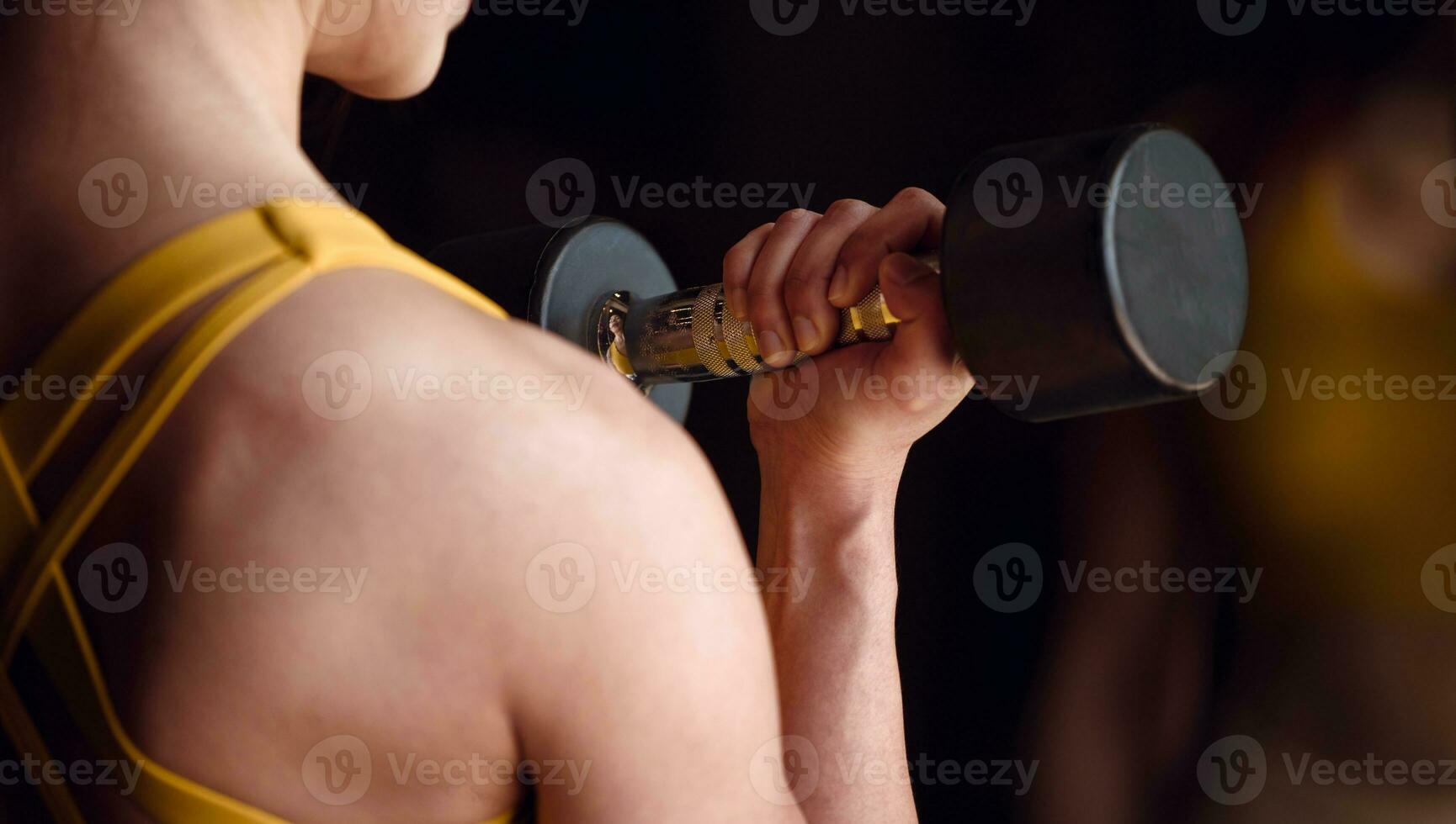 ung kvinna håller på med övning med hantel i främre av en spegel i de Gym. foto