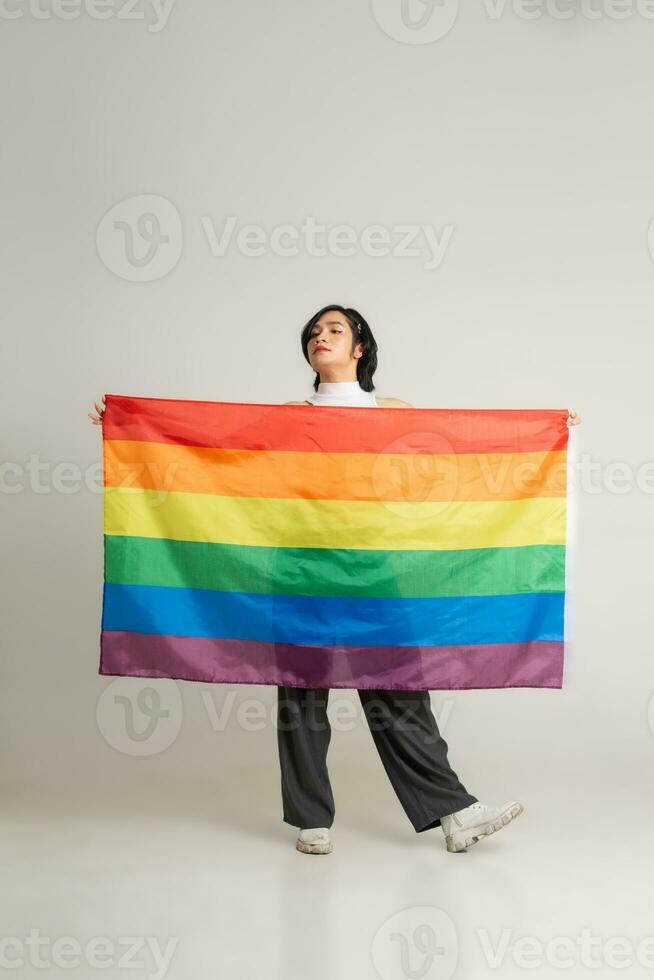 bild av asiatisk Gay man innehav en regnbåge flagga självsäkert Framställ på en vit bakgrund foto