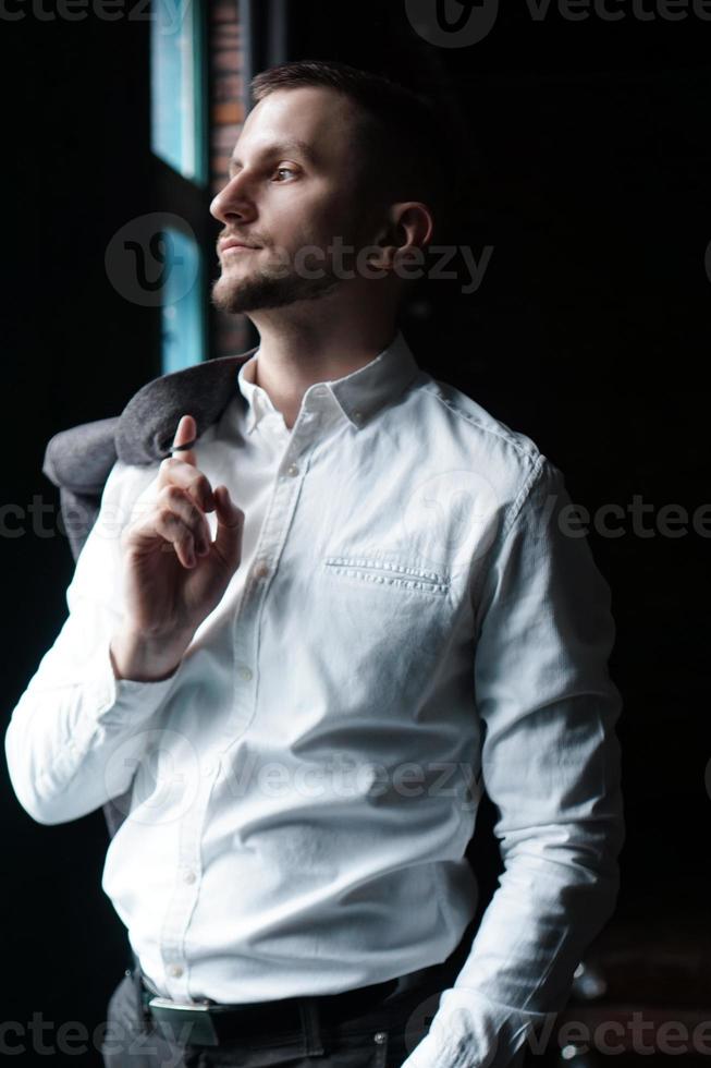 vy i profil av en ung affärsman som står nära fönstret foto