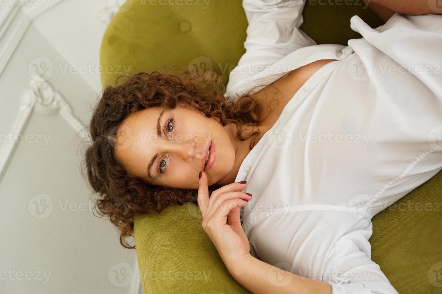 kvinna som sitter på den gröna soffan i vardagsrummet. vacker kvinna foto