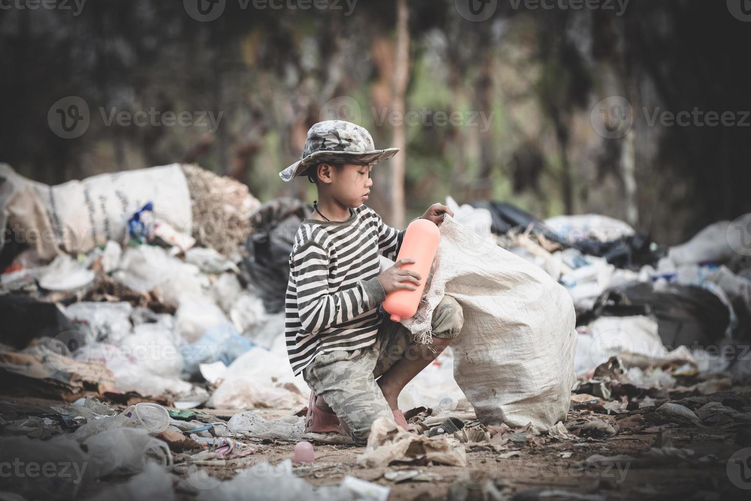 stackars pojke som samlar skräp i sin säck för att försörja sig. foto