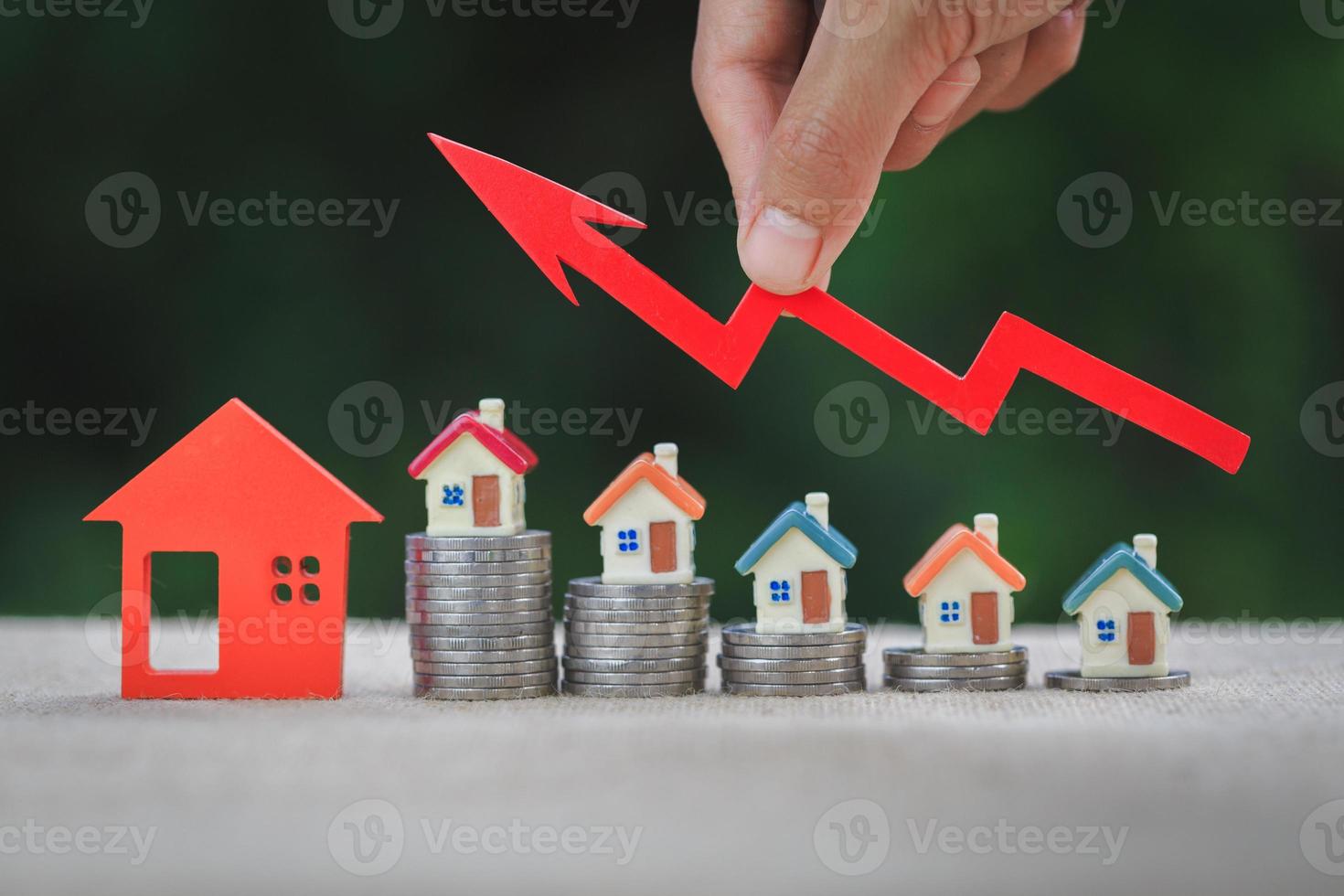 husmodell och en bunt mynt. fastighetsmarknaden, graf upp pil. begreppet inflation, ekonomisk tillväxt, fastighetsinvesteringar. foto
