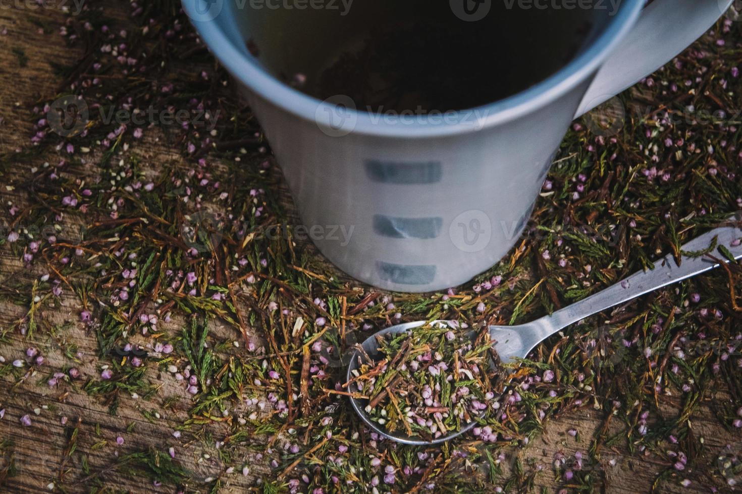 kopp och sked med blommigt te på en träbakgrund foto