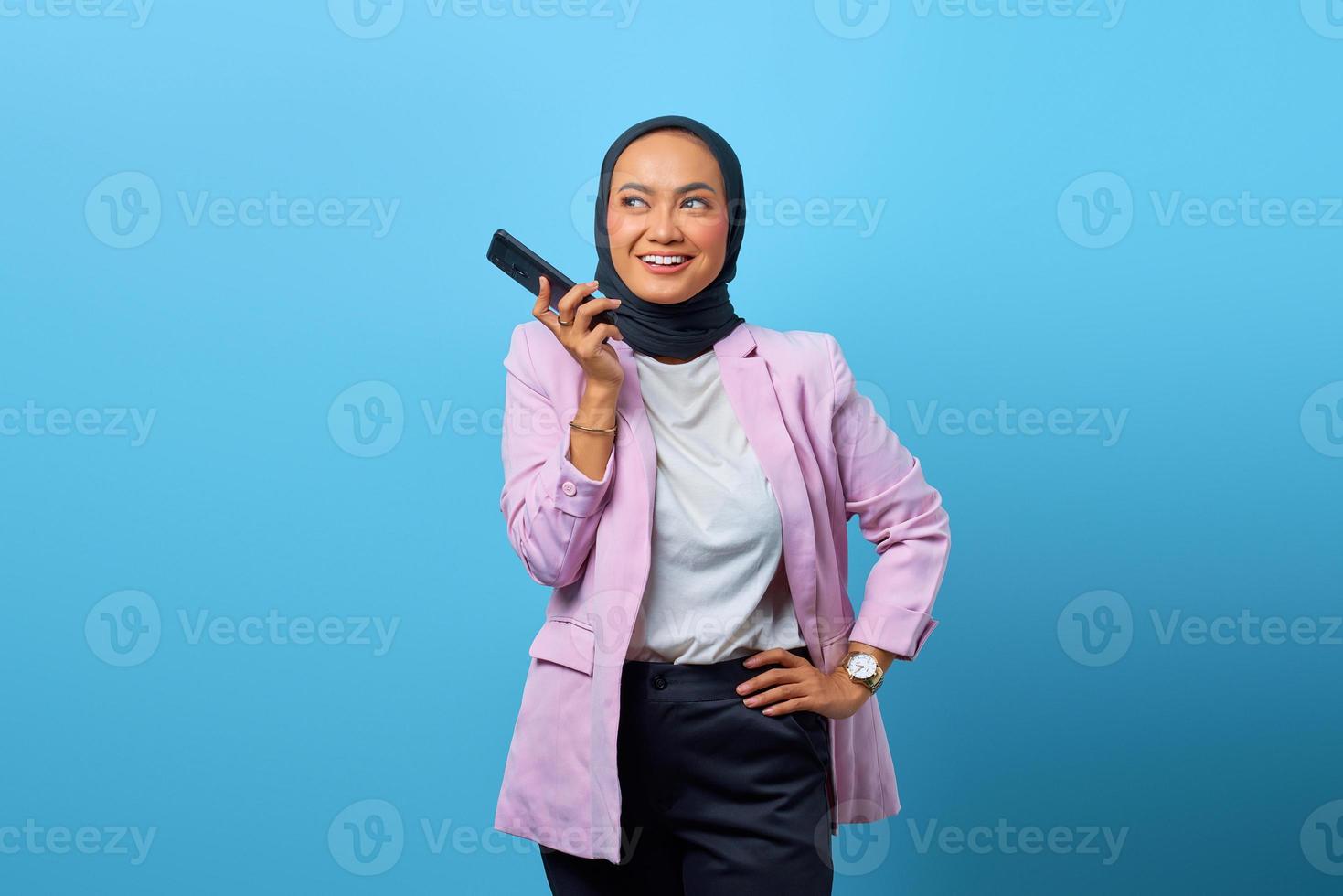 glad asiatisk kvinna som använder mobiltelefon över blå bakgrund foto