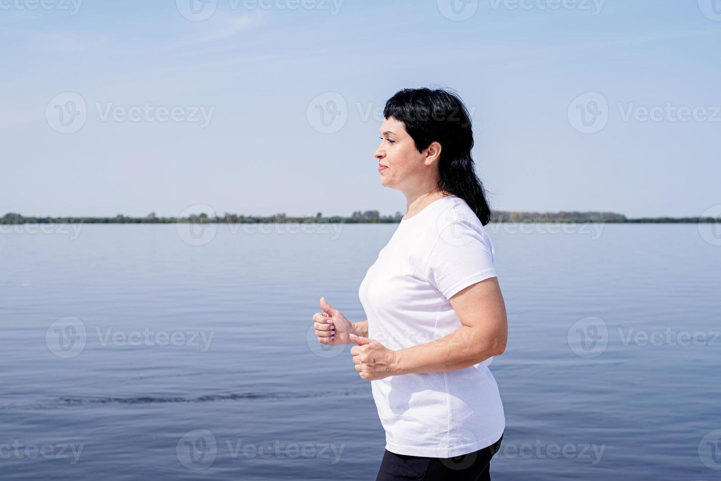 aktiv senior kvinna joggar nära floden foto