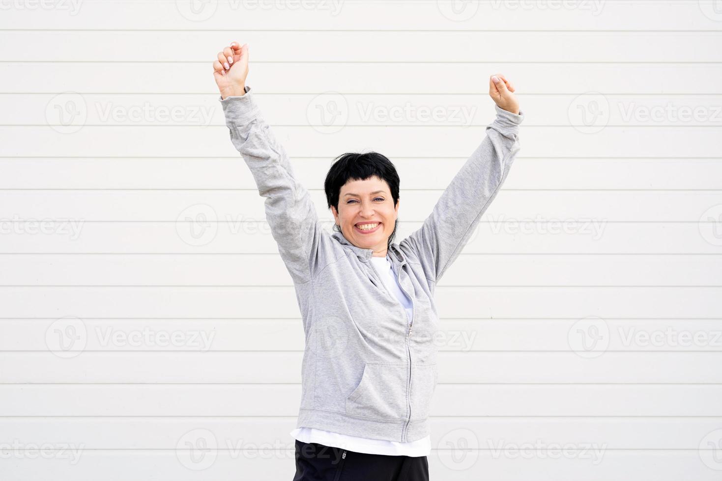 senior kvinna som sträcker ut armarna utomhus på idrottsplatsen foto