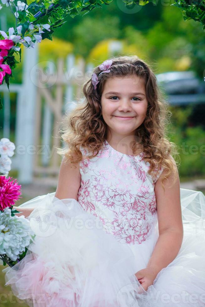 emotionell liten flicka i klänning Framställ med blommor foto