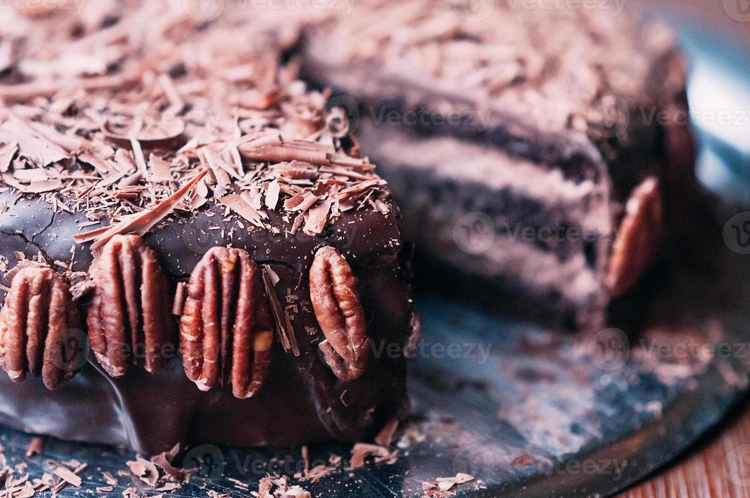 makrovy av utsökt mörk chokladkaka med chips, vacker glasyr och pekannötter på sidan på metallrätten. selektivt fokus. lyxig glasyr. bild för meny eller konfektkatalog foto