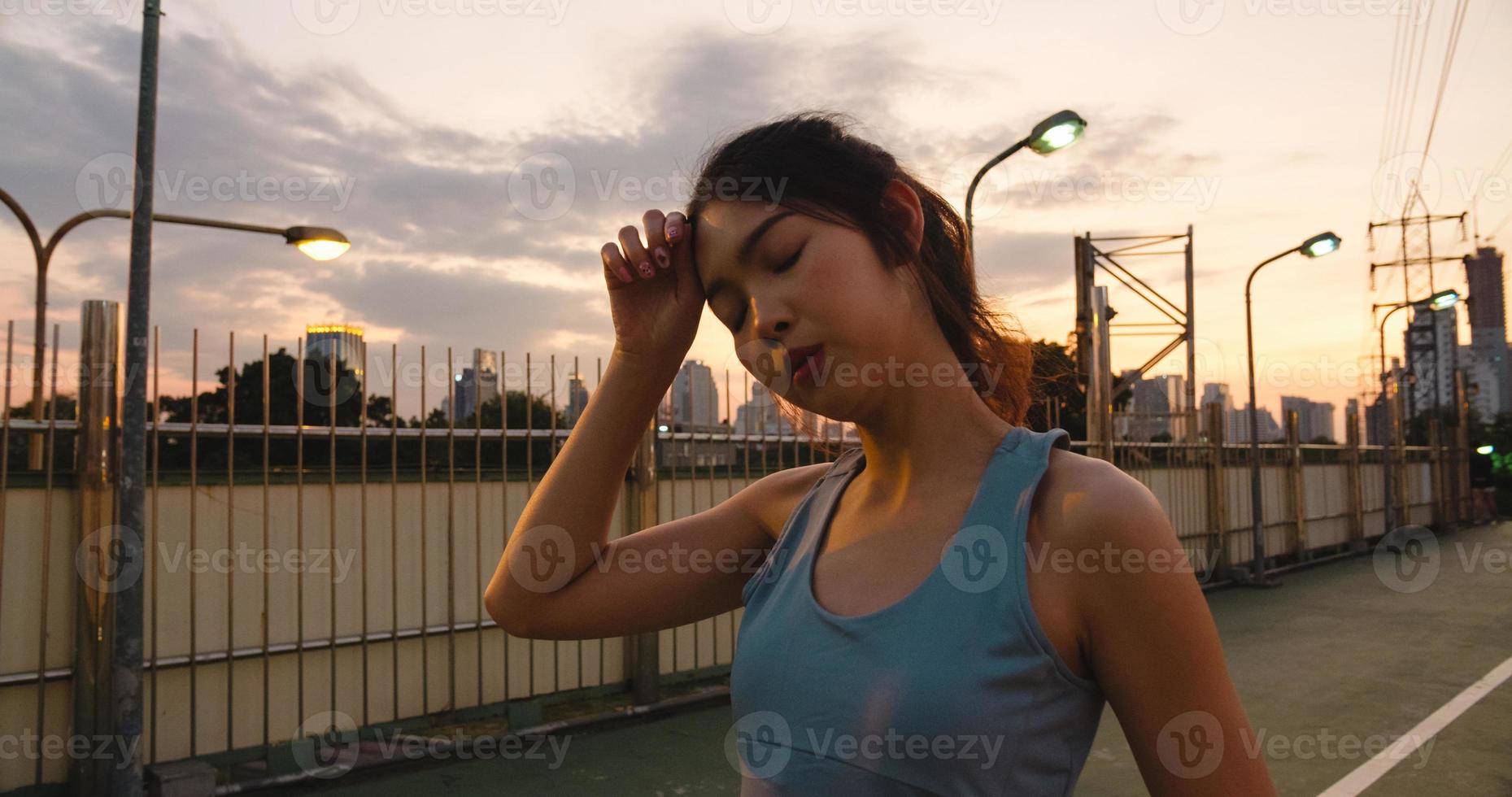 asiatisk idrottare dam övningar eftersom känner sig trött efter löpning. foto