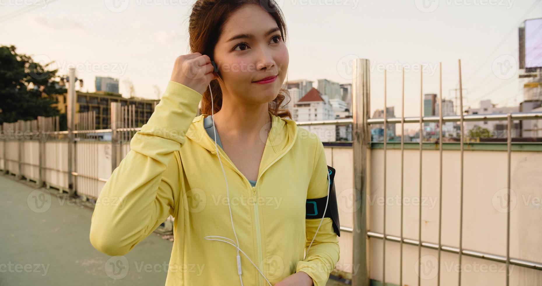 asien idrottsman dam övningar med smartphone för att lyssna på musik. foto