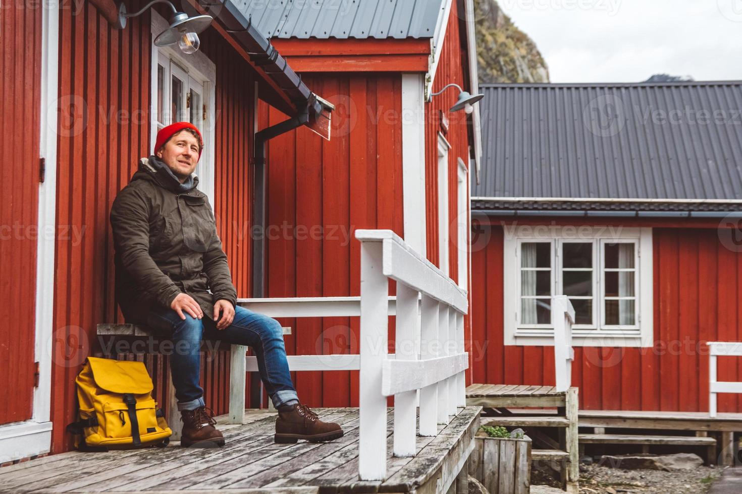 resenär man sitter nära trä rött hus foto