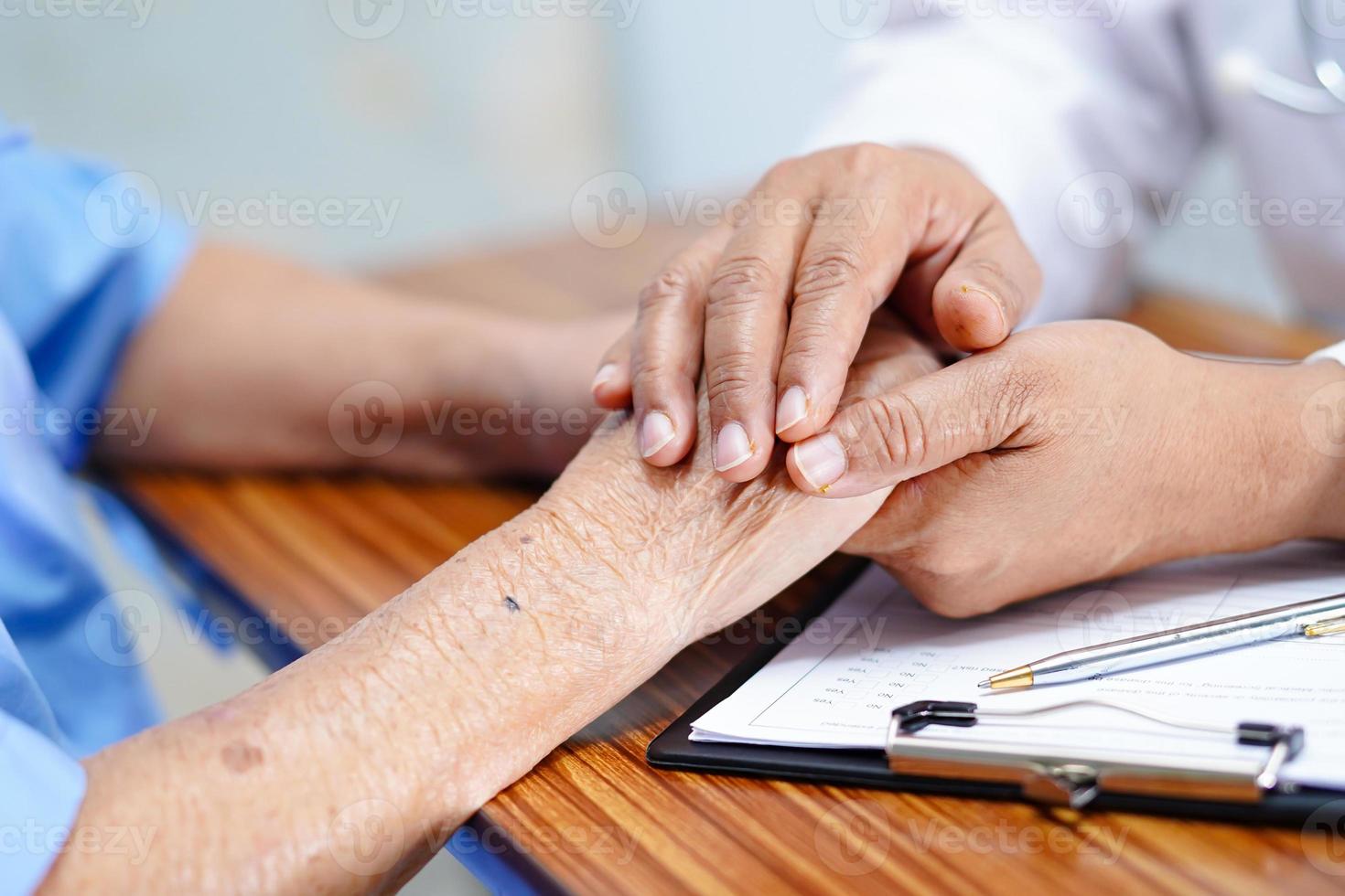 läkare som håller rörande händer asiatisk senior kvinna patient med kärlek foto