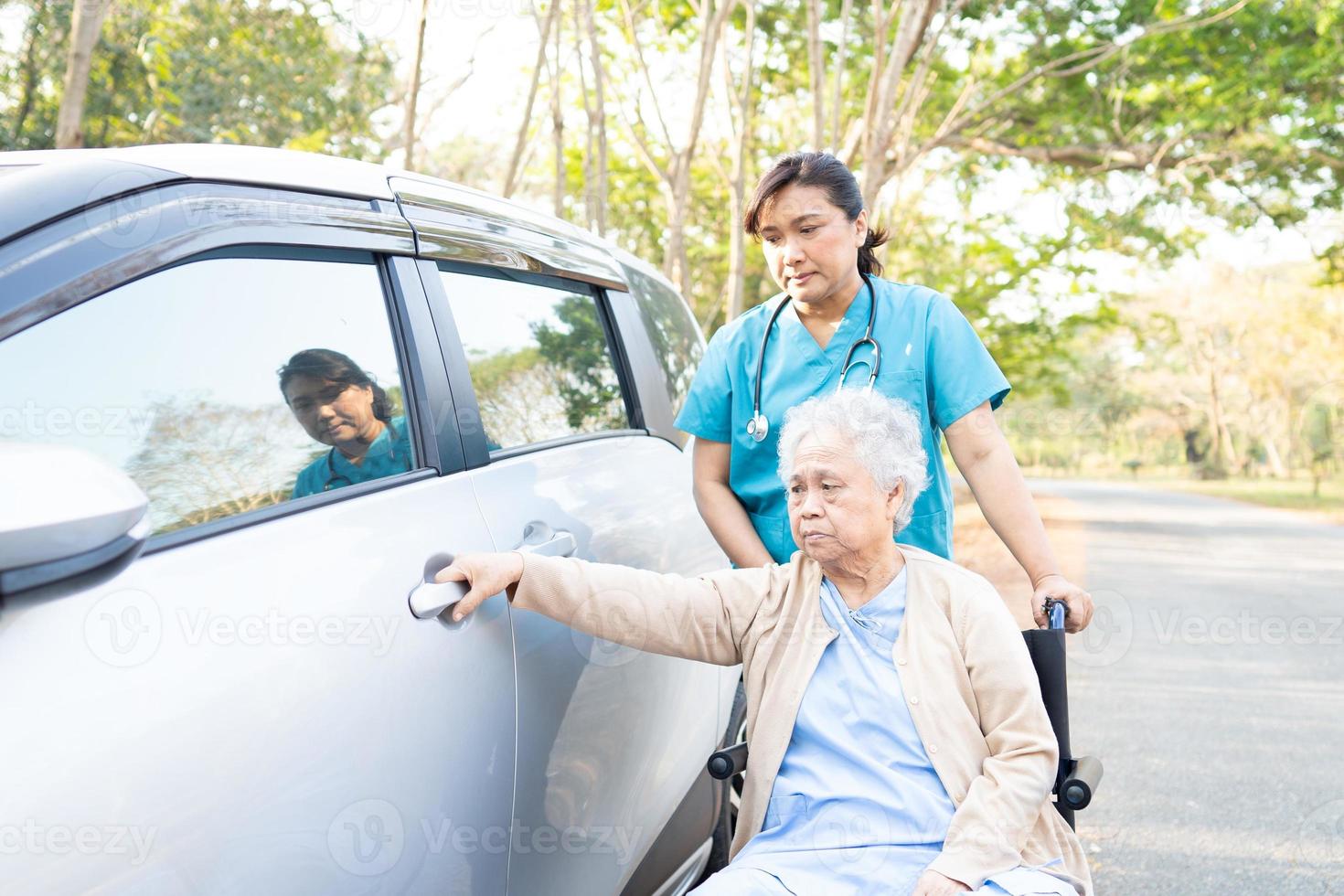 läkare hjälp asiatisk senior kvinna patient sitter på rullstol till bil foto