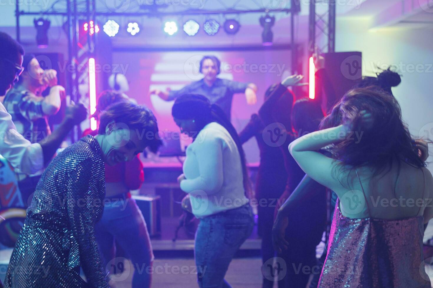 ung människor klubba och festa medan dans i nattklubb på elektronisk musik prestanda. olika folkmassan framställning rör sig på dansgolv medan har roligt och njuter nattliv foto