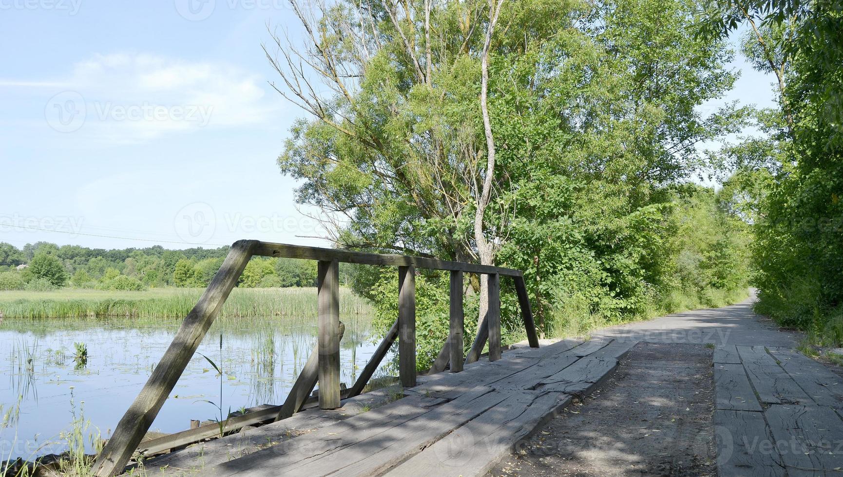 stående gammal träbro över floden i färgad bakgrund foto