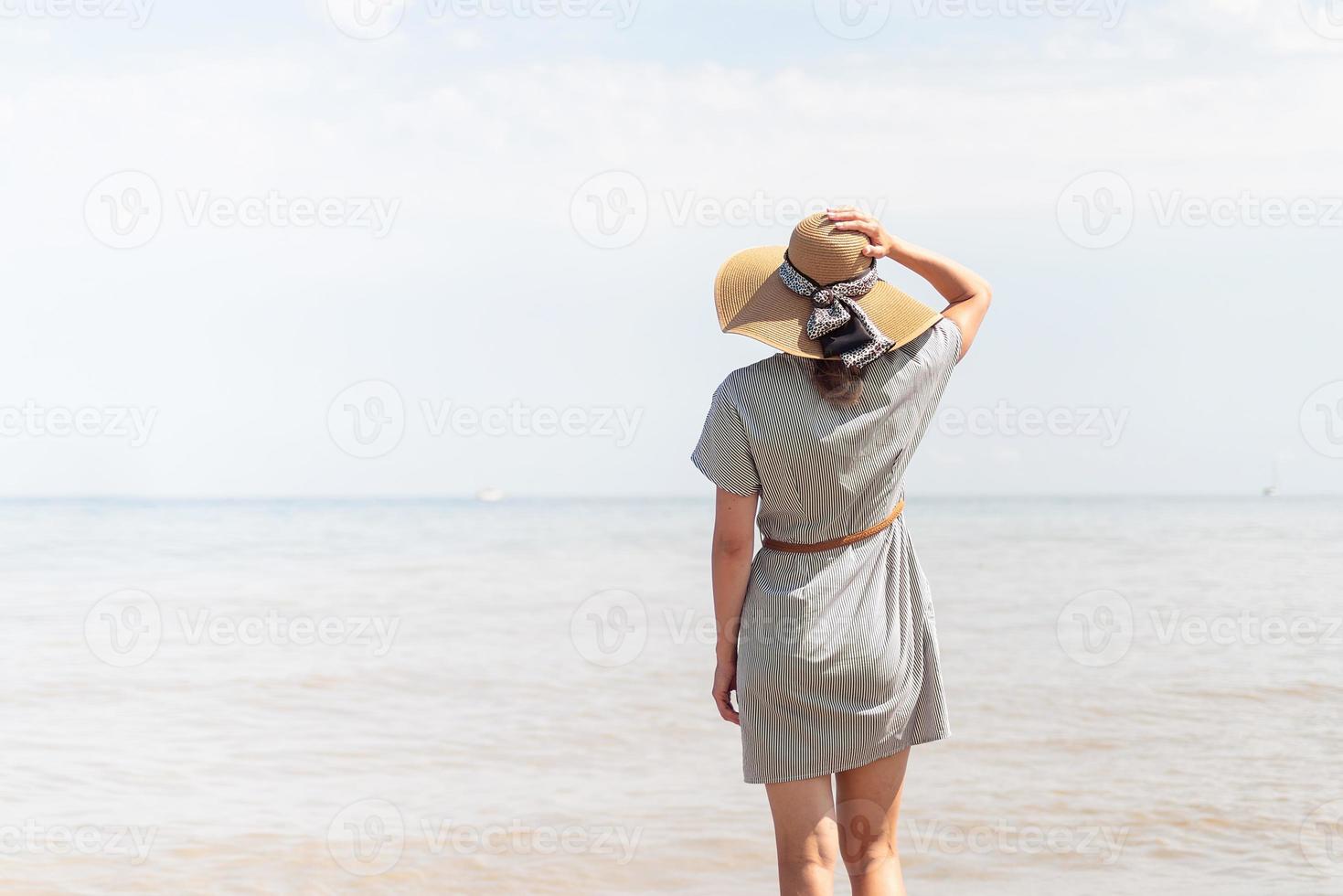 kvinna i sommarkläder som står på en pir, havet i bakgrunden foto