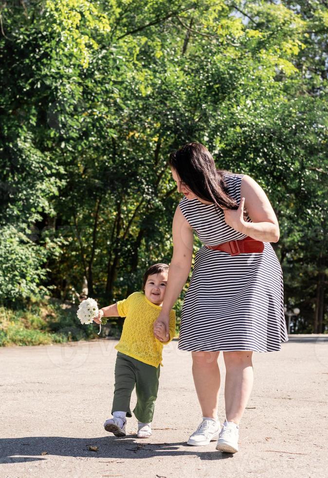 glad mångrasig familj av mor och dotter som går i parken foto