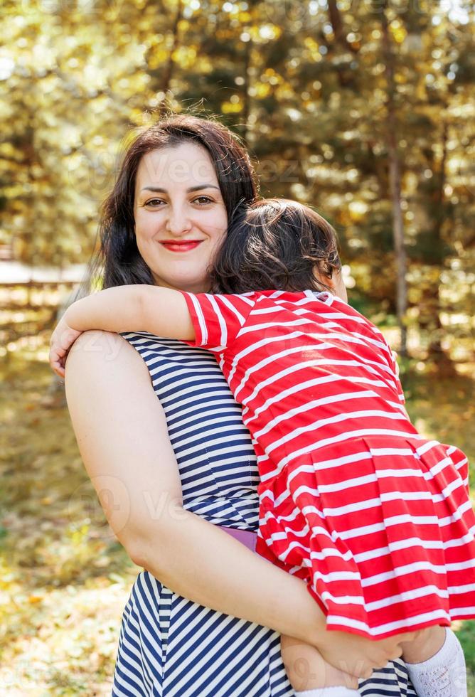 glad mångrasig familj av mor och dotter som går i parken foto