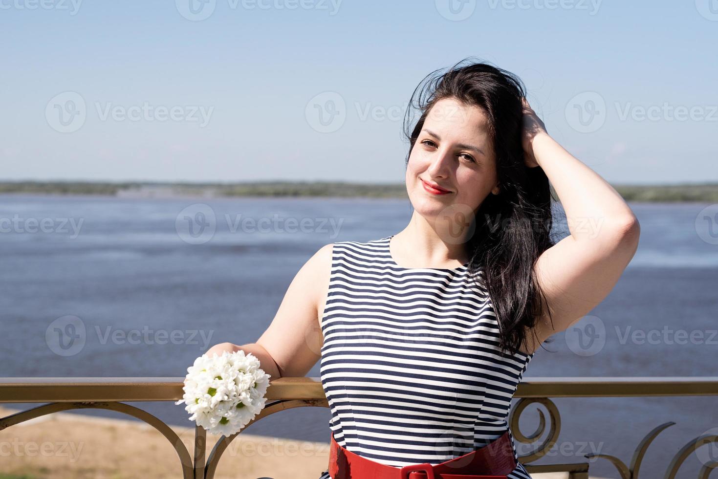 ung kvinna som håller blommor på flodbakgrund foto