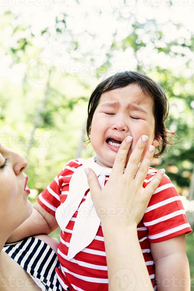 asiatisk flicka som gråter i moderhänder foto