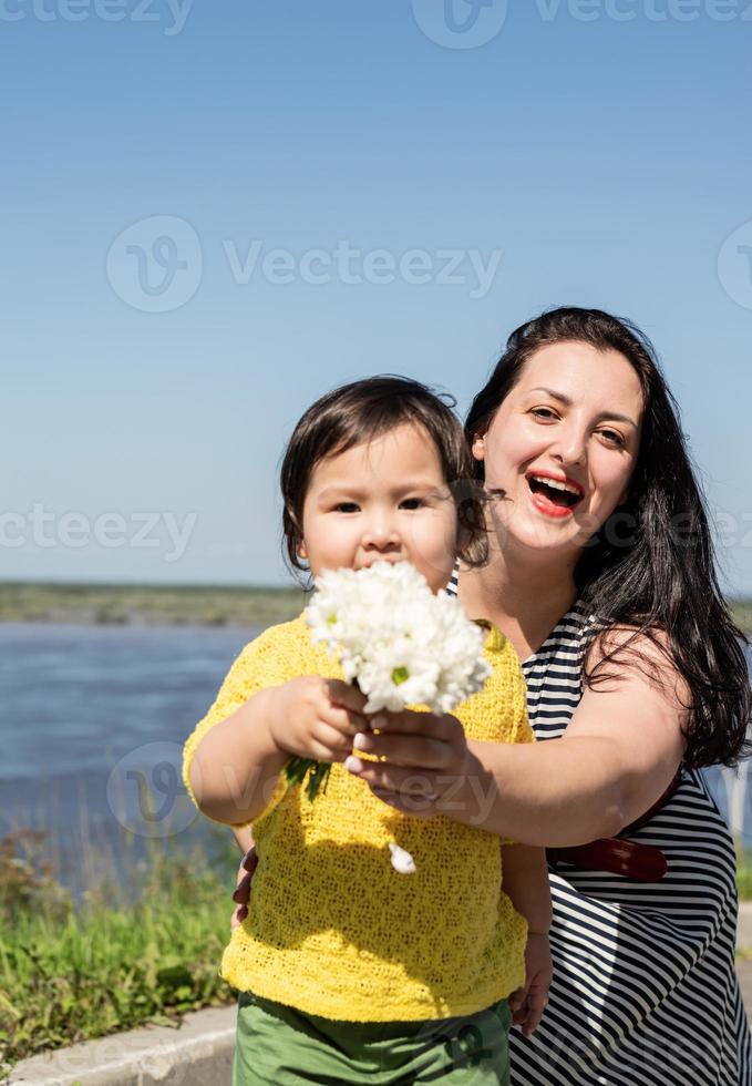 glad ung blandad etnisk familj som går i parken vid floden foto