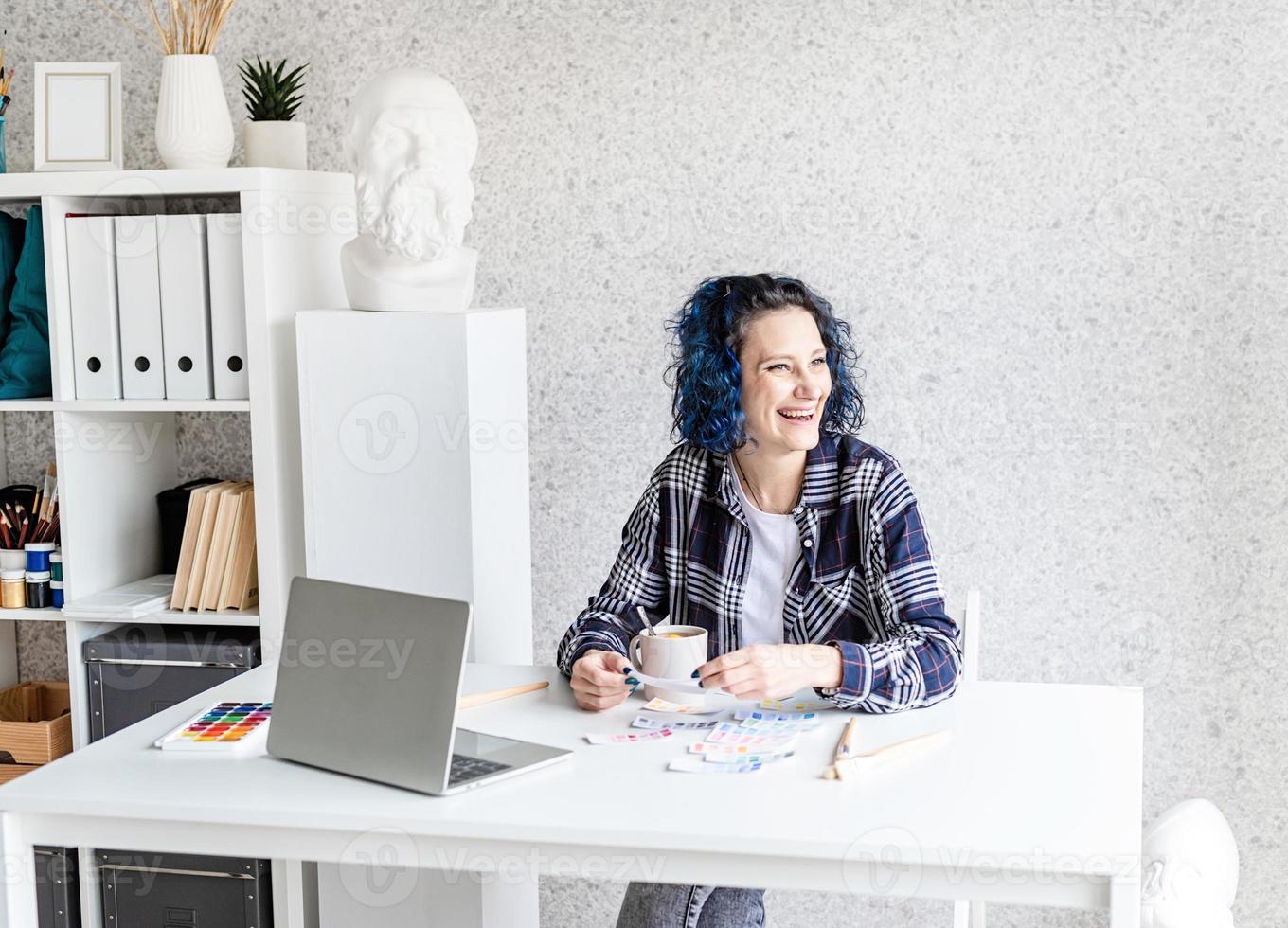 designer som arbetar med färgpaletter och bärbar dator i hennes studio foto