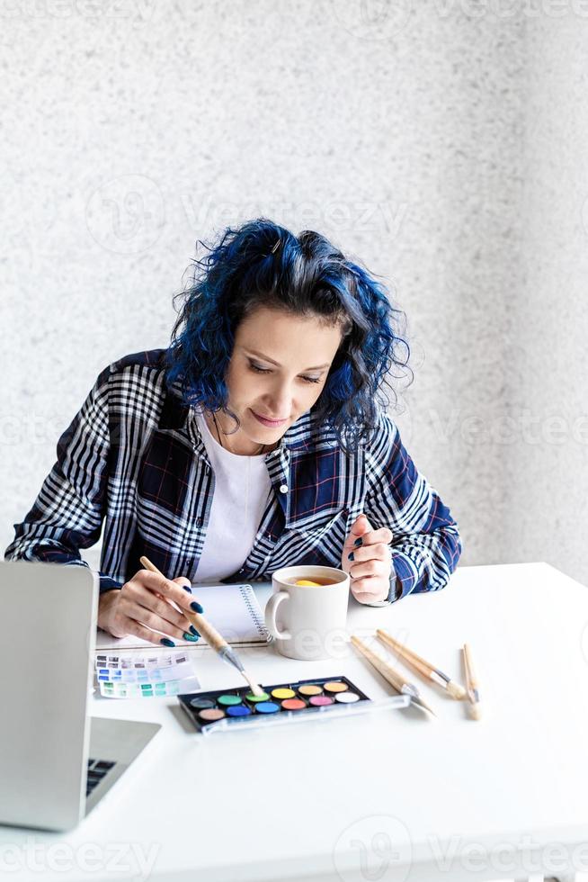 designer som arbetar med färgpaletter och bärbar dator i hennes studio foto