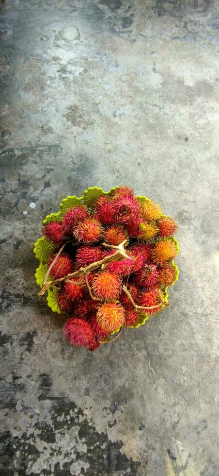 färsk och mogen rambutan ljuv tropisk frukt. rambutan frukt på korg golv bakgrund skörda från de trädgård rambutan träd foto
