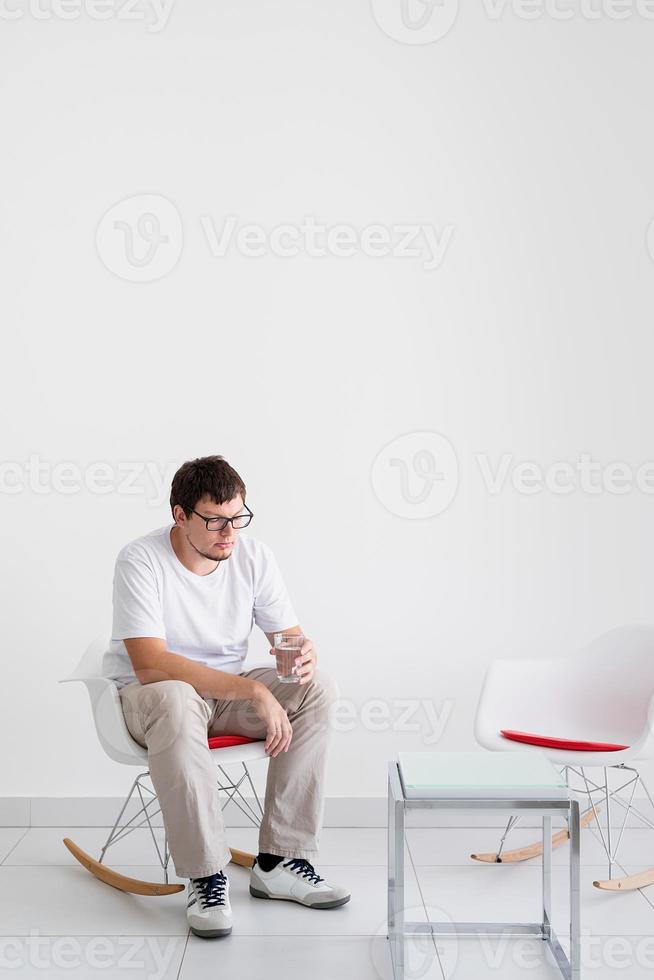 ung deprimerad man med huvudvärk som sitter på stolen foto