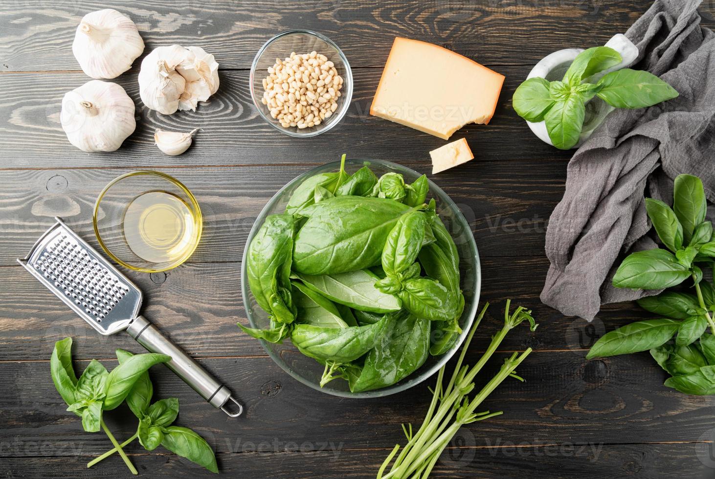 förbereder italiensk pestosås, basilika och ingredienser på svart bord foto