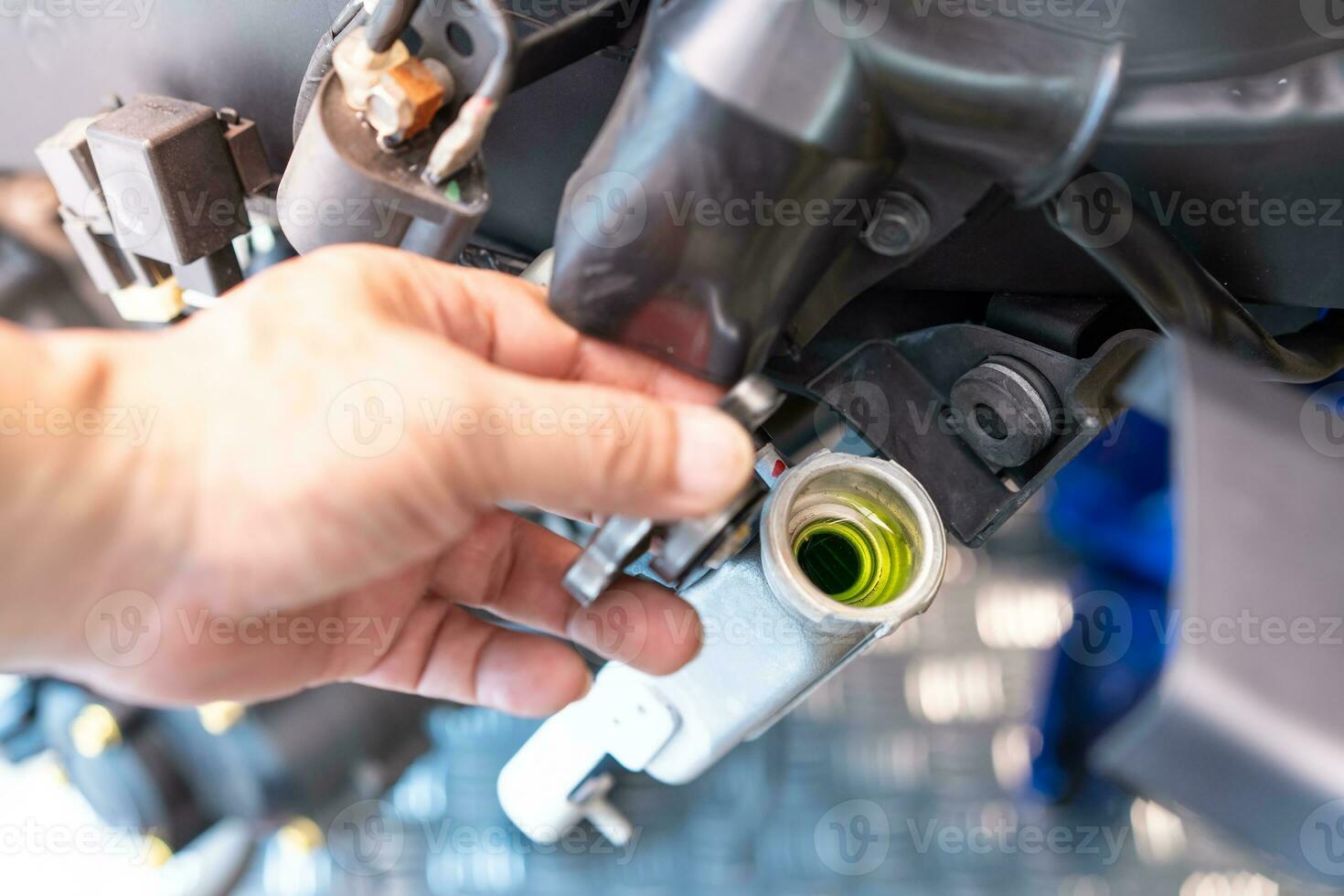 cyklist avlägsnande de keps från en kall radiator och kolla upp kylmedel vätska nivåer i motorcykel på garage, motorcykel underhåll och reparera begrepp. foto