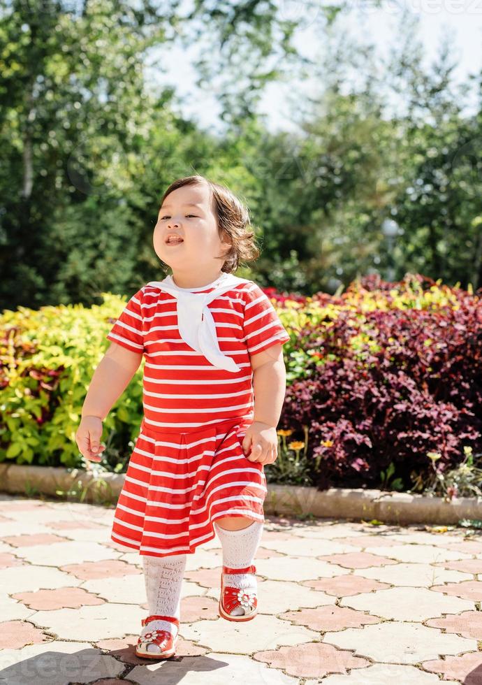 bedårande asiatisk spädbarn flicka dansar i parken foto