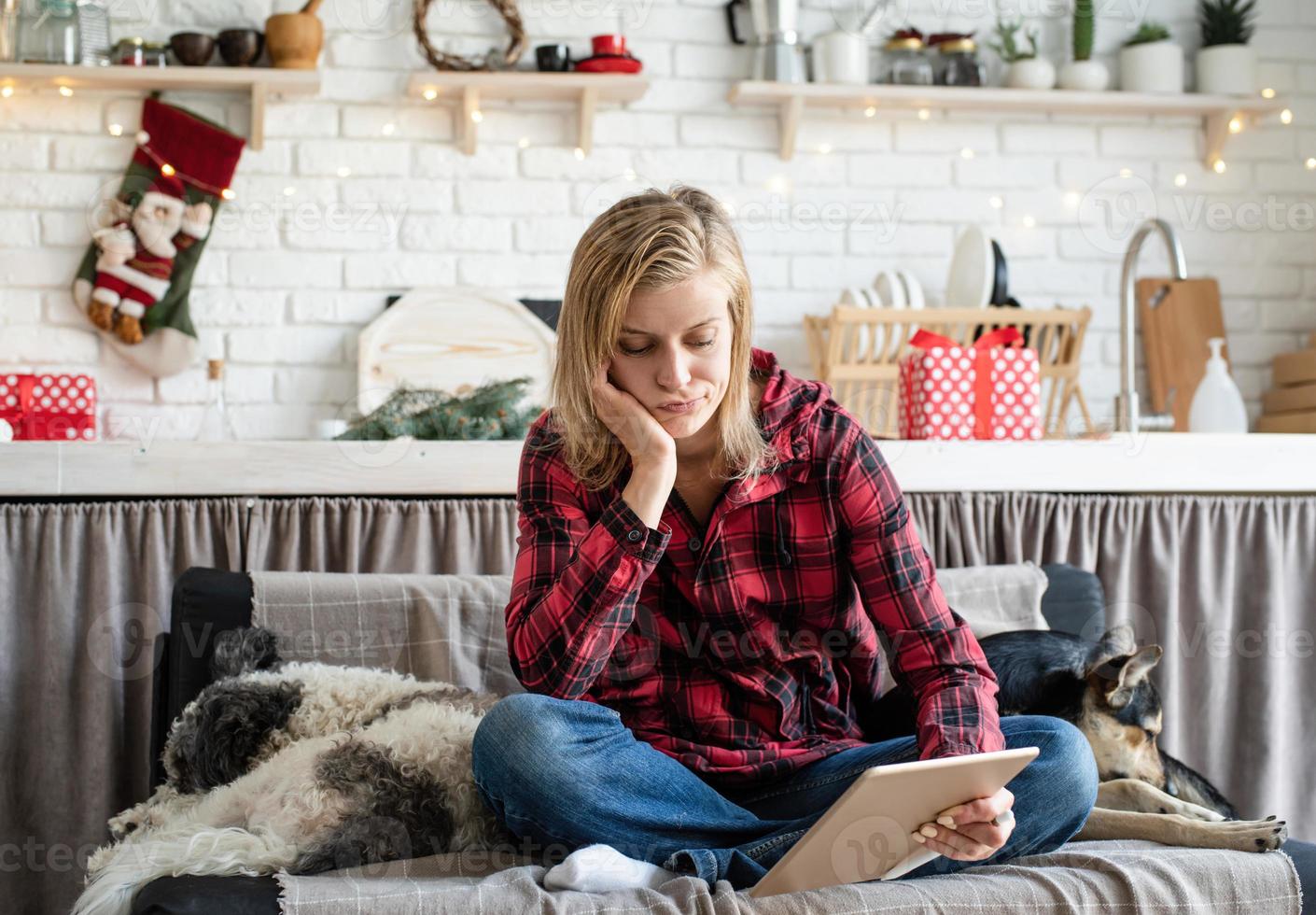 ung ledsen kvinna som arbetar på surfplattan som sitter i soffan foto