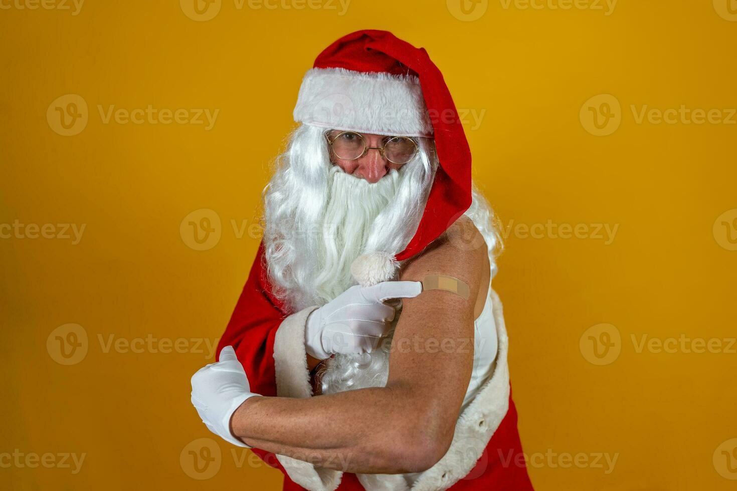 porträtt av Lycklig santa claus efter har covid-19 vaccination - santa som visar hans ärm med en plåster under de jul högtider foto