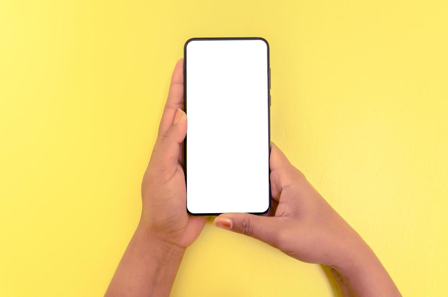 en hand som håller smartphone med vit skärmbakgrund. foto