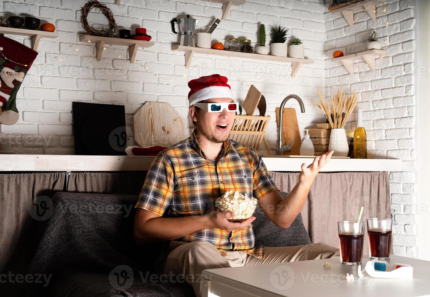 ung man i 3D -glasögon som tittar på filmer hemma på natten vid jul foto