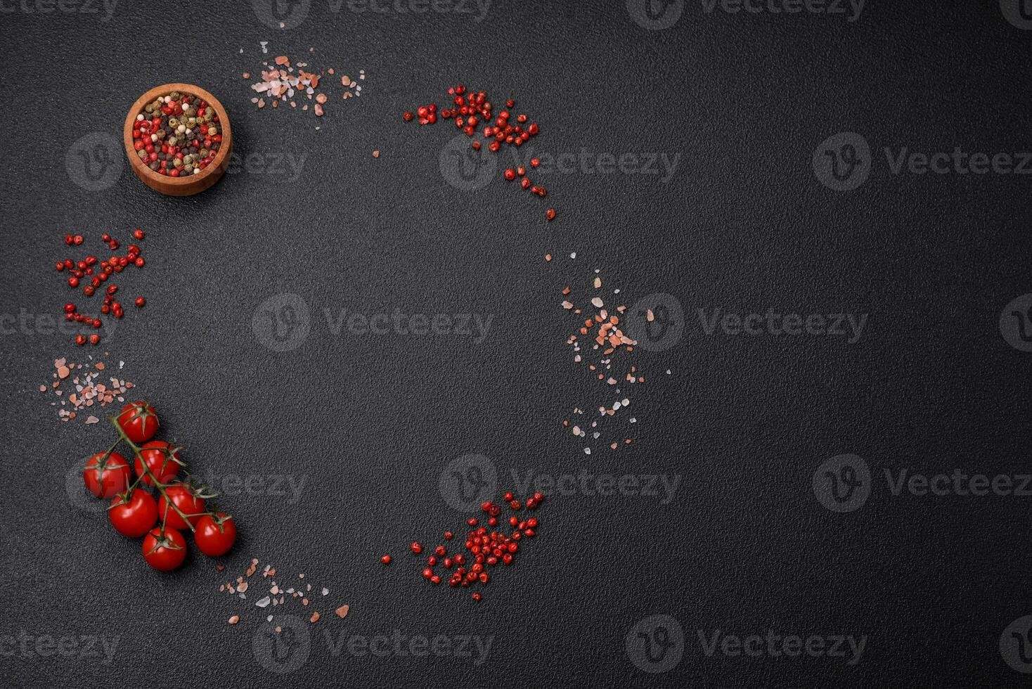 Ingredienser salt, kryddor, örter och tomater på en mörk betong bakgrund foto