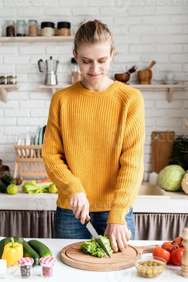 vacker kvinna som förbereder grekisk sallad i köket foto