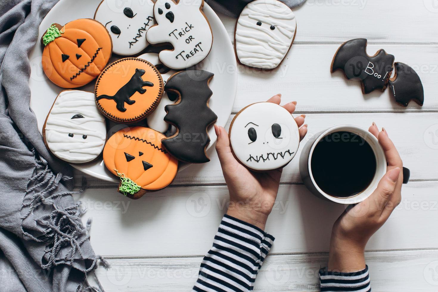 kvinna förbereder sig för halloween, dricker kaffe med pepparkakor foto