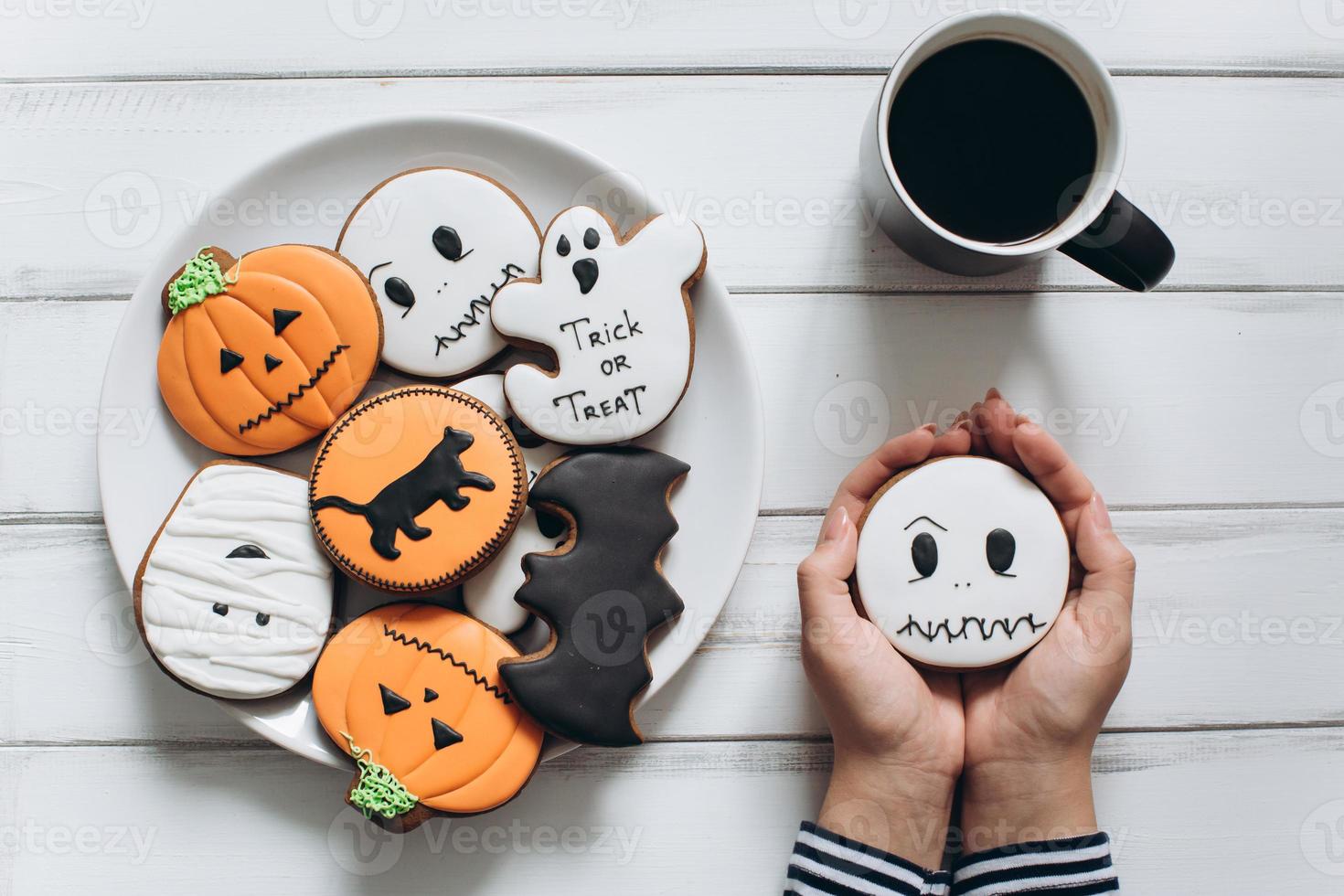 kvinna förbereder sig för halloween, dricker kaffe med pepparkakor foto